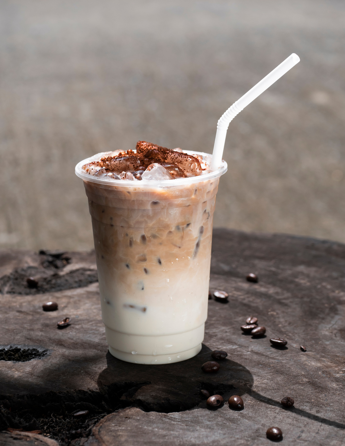 Cappuccino iced coffee with coffee beans on the wooden table. vertical photo